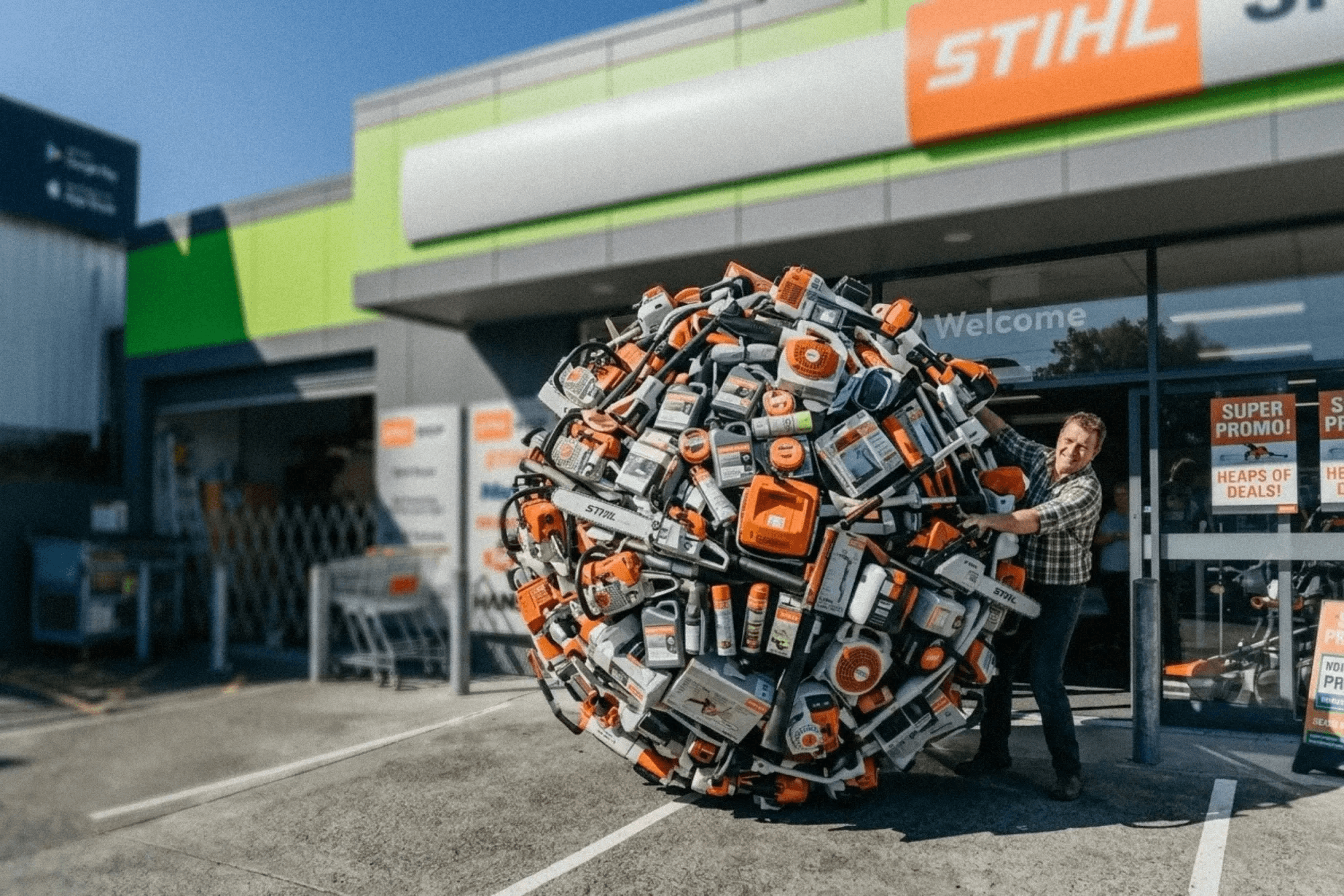 STIHL SHOP Tauranga staff member carrying an armload of STIHL outdoor power tools outside the store