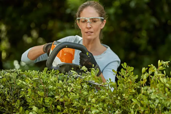 Person using a STIHL brushcutter in tall grass